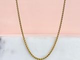 un collier à chaîne en or sur fond rose