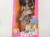 La poupée Barbie se trouve dans une boîte rose et porte une robe dorée.