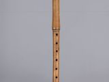 a wooden flute on a clear surface with a gray background