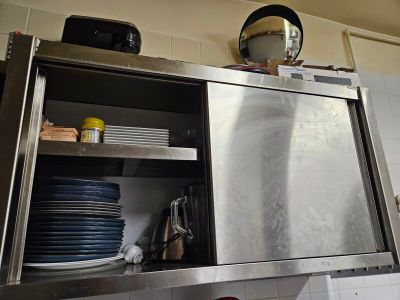 un placard en acier inoxydable dans la cuisine, avec de la vaisselle posée sur le plan de travail