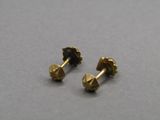 une paire de petites boucles d'oreilles en or sur un fond gris