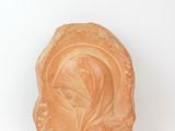 une sculpture orange représentant la tête d'une femme sur un fond blanc