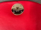 the red purse has a metal button on the front of it