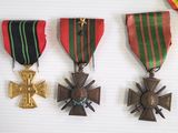 three medals and a cross on a white surface