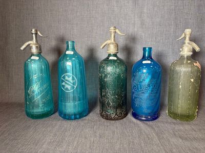 Quatre bouteilles en verre de couleurs différentes sont alignées les unes à côté des autres.