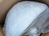 a large white object in a cardboard box wrapped in plastic