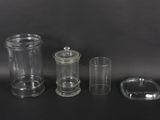 three clear glass containers with lids and lids on a black surface
