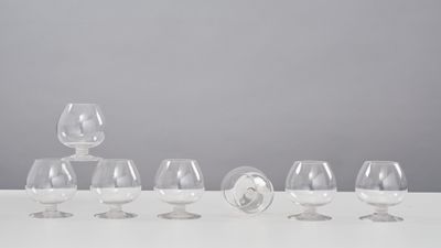 six empty wine glasses lined up in a row on a white table