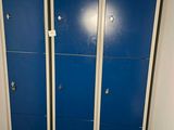 trois casiers bleus dans une salle de bains, à côté des toilettes