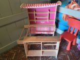two wooden chairs and a table with a doll house on it
