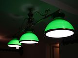 three green lamps hanging from the ceiling in a dark room