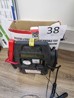 une boîte contenant une batterie et un chargeur, posée par terre