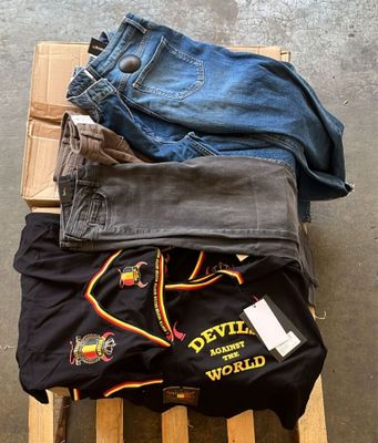 Plusieurs paires de jeans sont empilées sur une palette en bois
