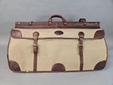 an image of a tan and brown suitcase sitting on top of a table