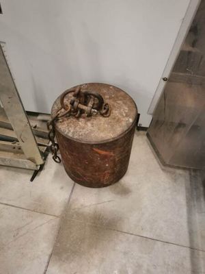 un conteneur métallique rouillé posé par terre à côté d'une porte