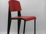 the chair is made of wood and has a red leather seat