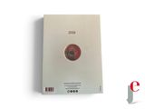 a close up of a book on a white surface with a red dot