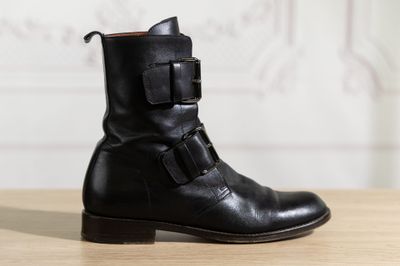 black leather ankle boots with buckles on top of a wooden table