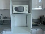 a microwave that is on top of a shelf in the kitchen