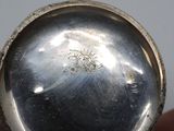 someone is holding a silver pocket watch in their hand