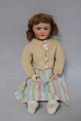 a doll that is sitting on the floor wearing a dress