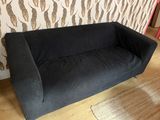 a black couch sitting in front of a zebra print wallpaper