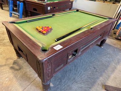 une table de billard recouverte d'un tapis vert, dans une pièce