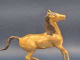 statue d'un cheval jaune sur un socle noir, sur fond bleu