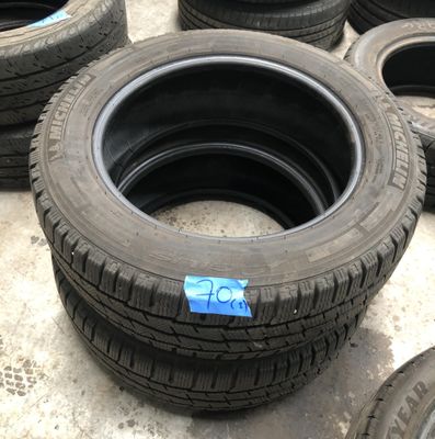 Plusieurs pneus sont alignés par terre, chacun muni d'un autocollant bleu.