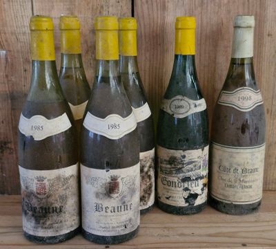 several bottles of wine are lined up on a wooden shelf