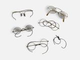 plusieurs paires de lunettes posées sur une surface blanche, sur fond blanc