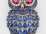 an image of a blue and white owl broochle with red eyes