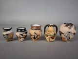 five vases with different designs on them sitting on a table