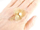 a woman ' s hand holding a ring with a pearl in it
