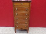a small wooden chest of drawers with marble top