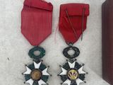 two medals and a case are sitting on a white surface