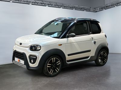 La petite voiture blanche est garée dans une grande pièce blanche.