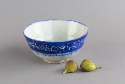 un bol bleu et blanc, avec deux figurines à côté