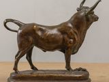 bronze statue of a bull on a wooden base on a table