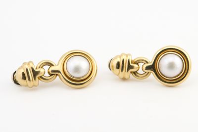 une paire de boucles d'oreilles en or et perles sur fond blanc