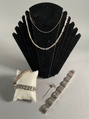 silver necklace, bracelet, and ring on a display stand