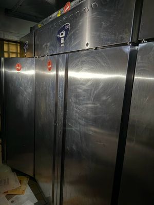 Plusieurs réfrigérateurs en acier inoxydable sont alignés dans une pièce