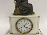 une statue de femme assise au sommet d'une horloge