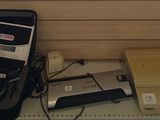 une photo montrant une valise et d'autres appareils électroniques posés sur une étagère