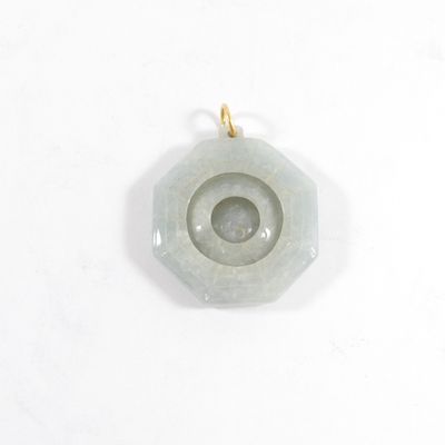 un gros plan d'un pendentif en pierre verte posé sur une surface blanche