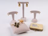 trois paires de boucles d'oreilles et un sac à main posés sur une surface blanche