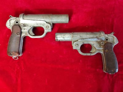 an old gun and a smaller gun on a red cloth