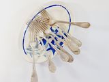 a lot of silver spoons and forks in a blue and white bowl