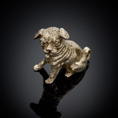 une figurine en or représentant un chien assis sur une surface noire