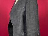 a gray jacket on a mannequin stand against a red background